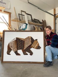 a woman kneeling next to a bear cut out of wood