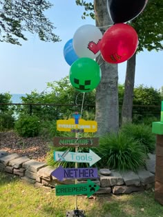 a bunch of balloons that are on top of a sign in front of a tree