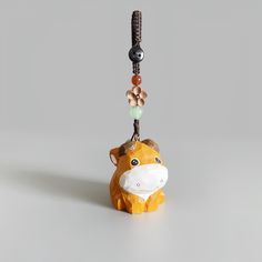 a toy cow hanging from a string on a gray background