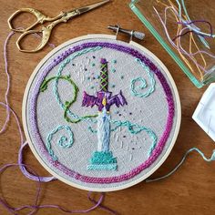 an embroidery project with scissors and thread on a wooden table next to some other items