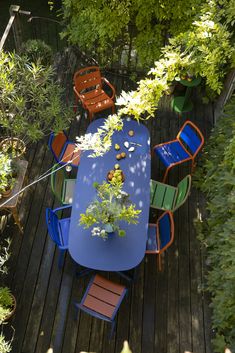 an overhead view of a table and chairs on a wooden deck surrounded by greenery