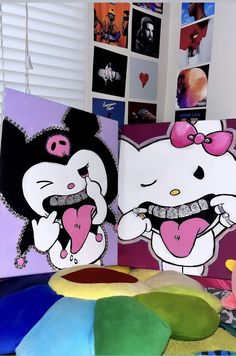 there are two hello kitty paintings on the table next to each other and one is holding a heart