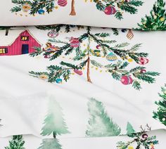 a white sheet with christmas trees on it and a red barn in the background,