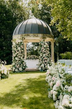 a gazebo covered in white flowers and greenery