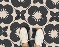 a person standing in front of a black and white tile floor with flowers on it