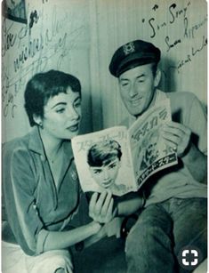 an old black and white photo of a man reading a magazine to a woman