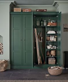 a green cabinet with lots of items in it and some baskets on the floor next to it