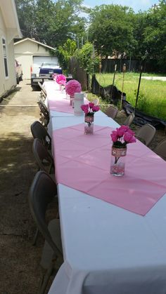 a long table with pink flowers in vases on it