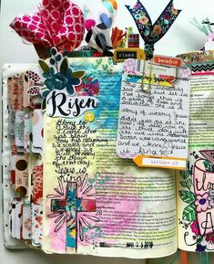 an open bible with paper flowers and other things on the pages that are attached to it