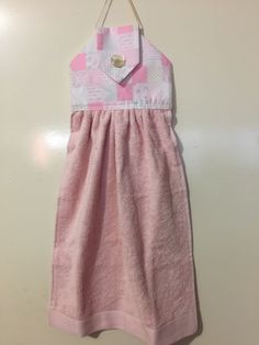 a pink and white baby's dress hanging from a hook on a door hanger