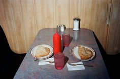 a table topped with plates and cups filled with food next to a red shaker