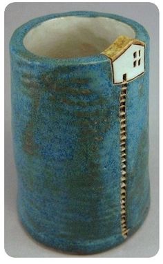 a blue vase with a small house on the inside and zippered in to it