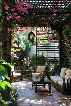 an outdoor seating area with flowers on the pergolated wall and wooden benches