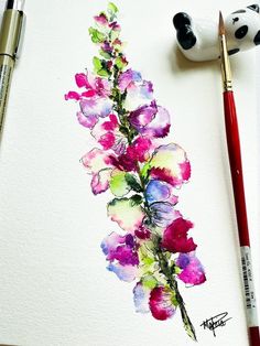 a watercolor painting of purple flowers on a white paper next to a paintbrush