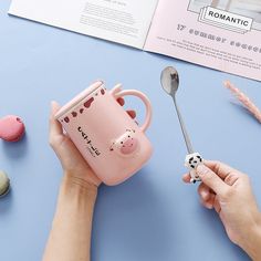 a person holding a pink coffee mug and spoon