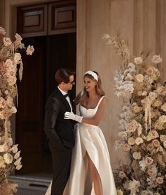 a man in a tuxedo and a woman in a wedding dress standing next to each other