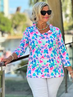 an older woman wearing white pants and a colorful shirt is walking down the street with her hand on a railing