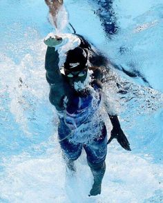 a man is swimming in the pool with his hands out to catch a frisbee