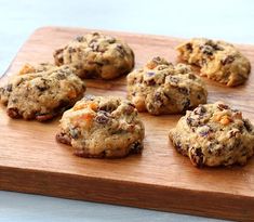 chocolate chip cookies are arranged on a wooden cutting board, ready to be baked or eaten