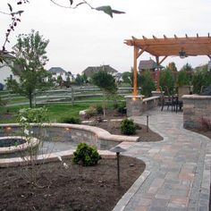 an outdoor patio with stone walls and brick walkway leading to a pergolated area