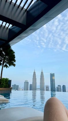 a person laying on the edge of a swimming pool in front of some tall buildings