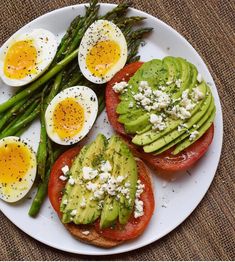 asparagus, tomato, and eggs on toast with avocado in the middle