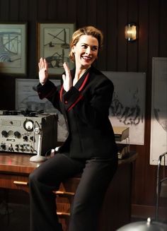 a woman sitting on top of a wooden table in front of a recording equipment set