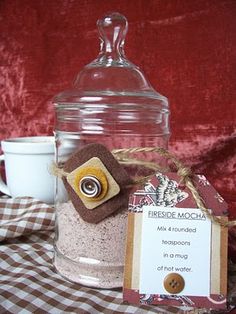 a glass jar filled with sand next to a cup and saucer on a checkered table cloth