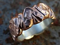 a close up view of a ring made out of silver and gold leafy material