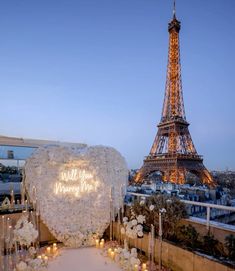 the eiffel tower is lit up at night with candles and flowers in front