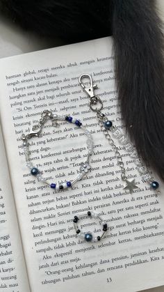 an open book with a cat's paw on top of it next to a bracelet