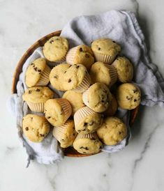 a basket filled with muffins sitting on top of a white marble countertop