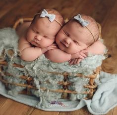 two twin babies are laying on top of each other in a basket with blue wool