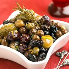 a white bowl filled with olives on top of a red table