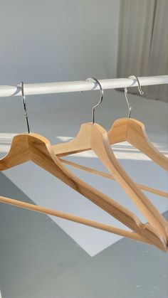 three wooden clothes hangers on a white rail