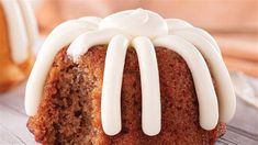 a bundt cake with white icing sitting on top of a wooden table