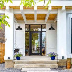 a white house with two blue planters on the front door and steps leading up to it