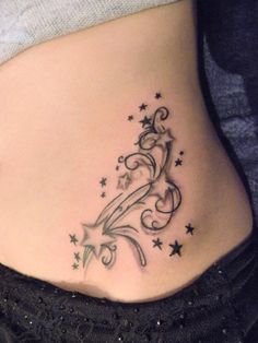 a woman's stomach with stars and swirls on the side, tattoo style