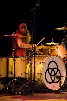 a man with long hair playing drums on stage