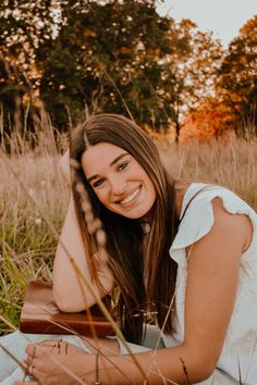 a beautiful young woman laying on top of a field