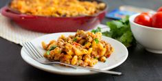 a white plate topped with macaroni and cheese next to a bowl of tomatoes