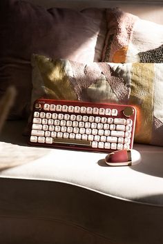 a red keyboard sitting on top of a white couch next to pillows and a pillow