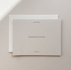 two cards with congratulations written on them sitting next to each other in front of a white wall