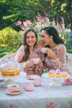 two women sitting at a table with tea cups