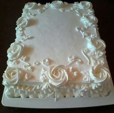 a square cake with white frosting roses on it