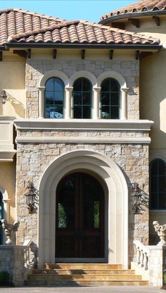 the front entrance to a large house with arched windows and stone steps leading up to it