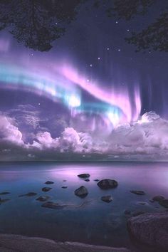 an aurora bore over the ocean with clouds and rocks