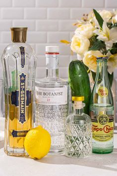 the bottles are lined up next to each other with lemons and gin in them