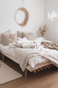 a bed with white linens and pillows in a bedroom next to a wooden floor