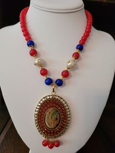 Hand painted portrait peacock necklace.  Beaded chain has 8mm to 10mm red/blue onyx and freshwater pearl.  Clear and orange Austrian crystal.  Gold electroplating. Multicolor Pearl Jewelry With Faceted Beads, Red Beaded Pendant Necklace For Festivals, Festive Multicolor Pearl Necklaces, Red Pearl Necklace With Round Beads, Elegant Handmade Red Beads, Gems, And Cabochons, Red Pearl Necklace With Pearl Chain, Festive Red Pearl Chain Jewelry, Festive Red Round Pendant Necklace, Red Pearl Beaded Necklaces With Pearl Chain